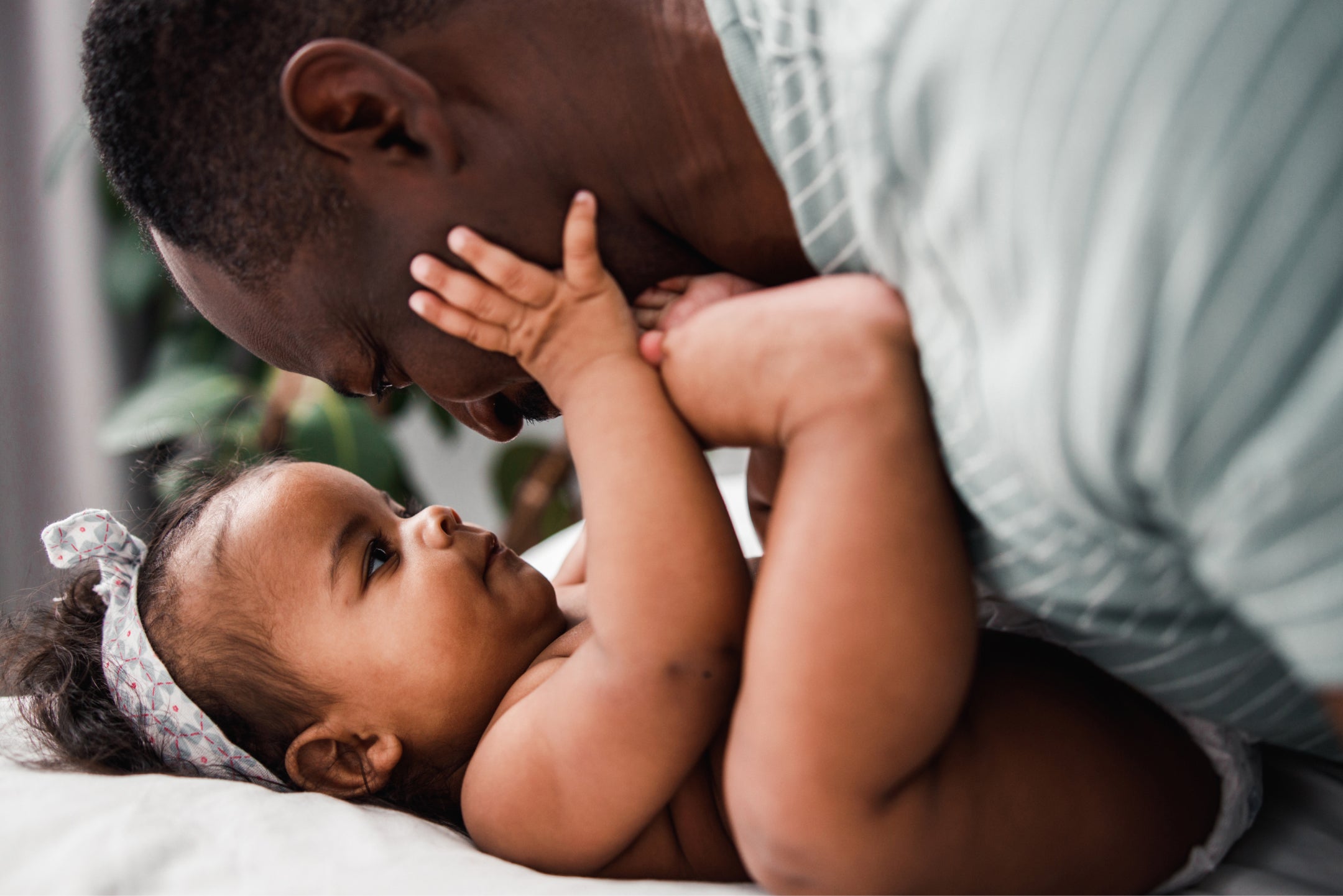 Black man with high cholesterol plays with baby on bed